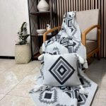 شال مبل طرح‌دار هندسی سایز دو نفره رنگ مشکی پهن شده روی کاناپه راحتی