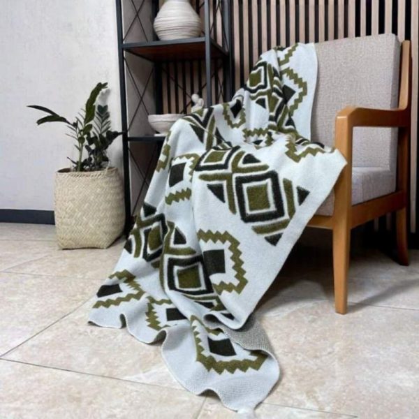 شال مبل طرح‌دار هندسی سایز دو نفره رنگ سبز زیتونی پهن شده روی کاناپه راحتی